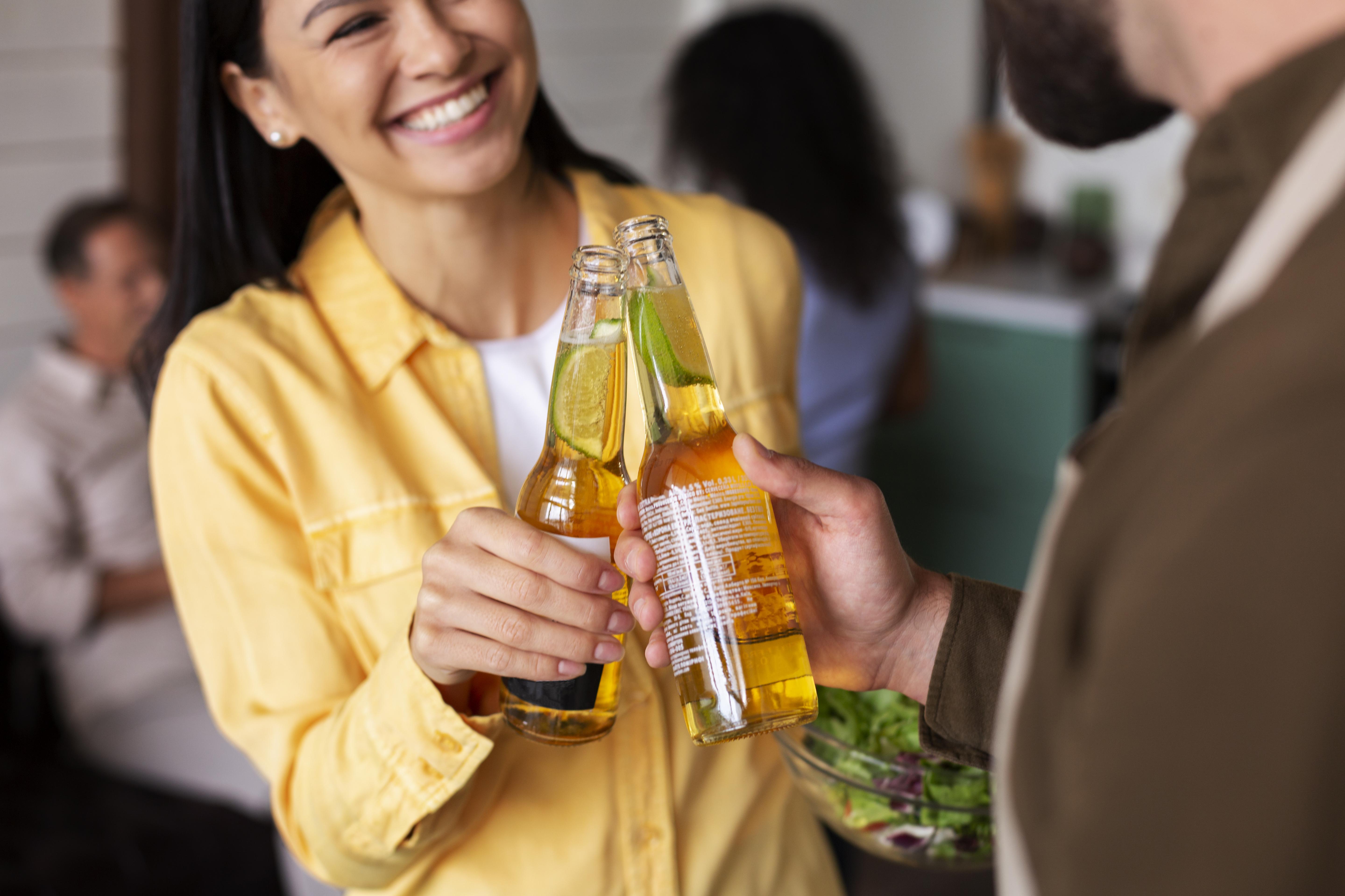 Homem e mulher brindam segurando cada um uma garrafa long neck de cerveja sem álcool